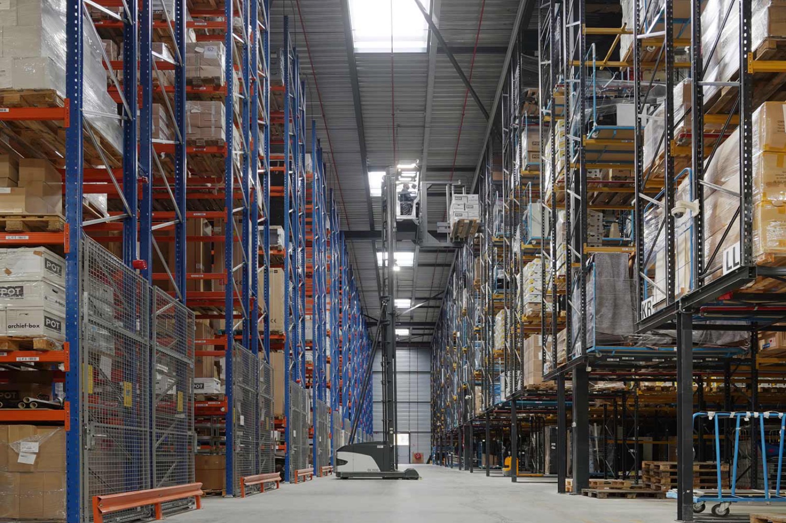 Magazijngang met stellingen en een orderpicker aan het werk